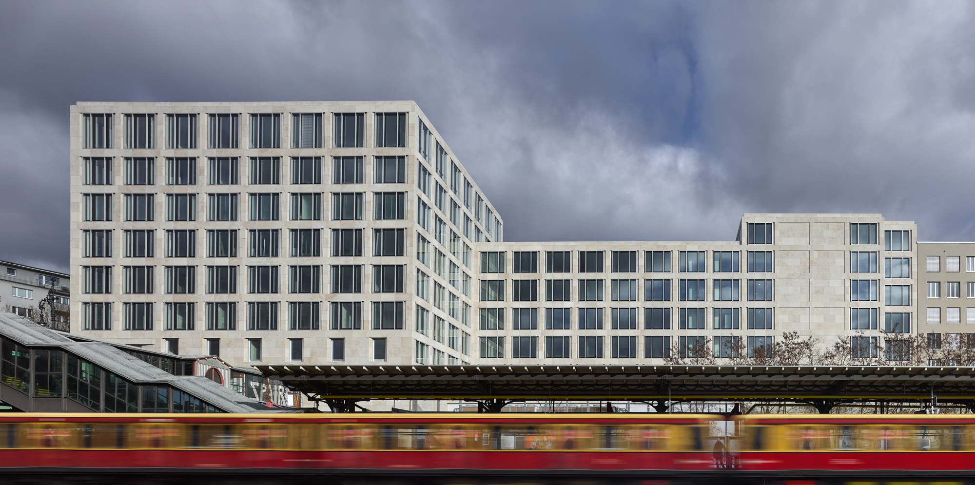 Büro- und Geschäftshaus am Kurfürstendamm Berlin - Das einheitliche Fassadenraster fasst die komplexe, stark gegliederte Großform zusammen. Die großen Kastenfenster werden bündig in die massiv wirkende Fassade aus Jurakalkstein eingesetzt, auch sie betonen den skulptalen Charakter des Gebäudes.